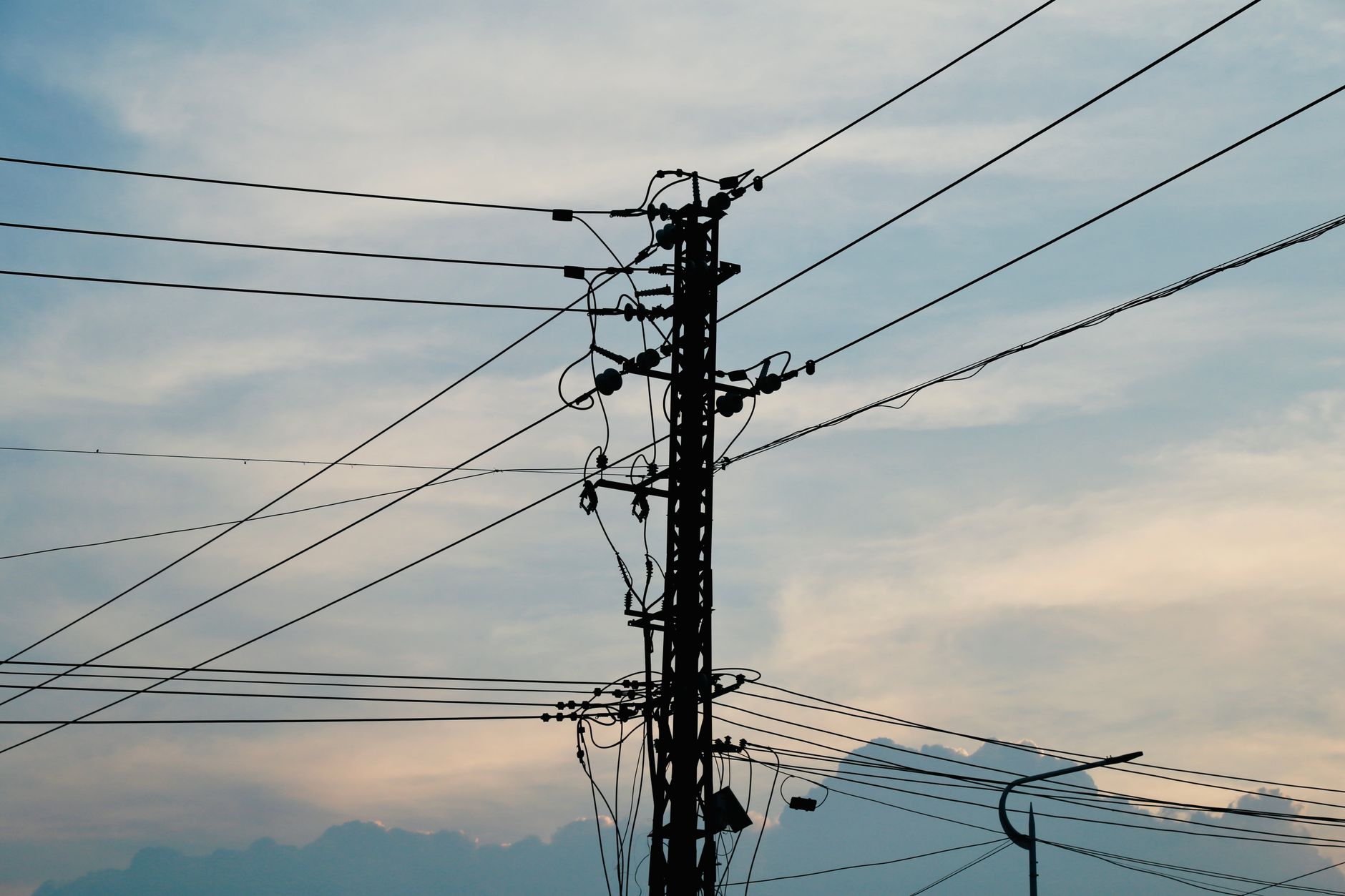 夕方の空を背景に電線が張られた電柱のシルエット