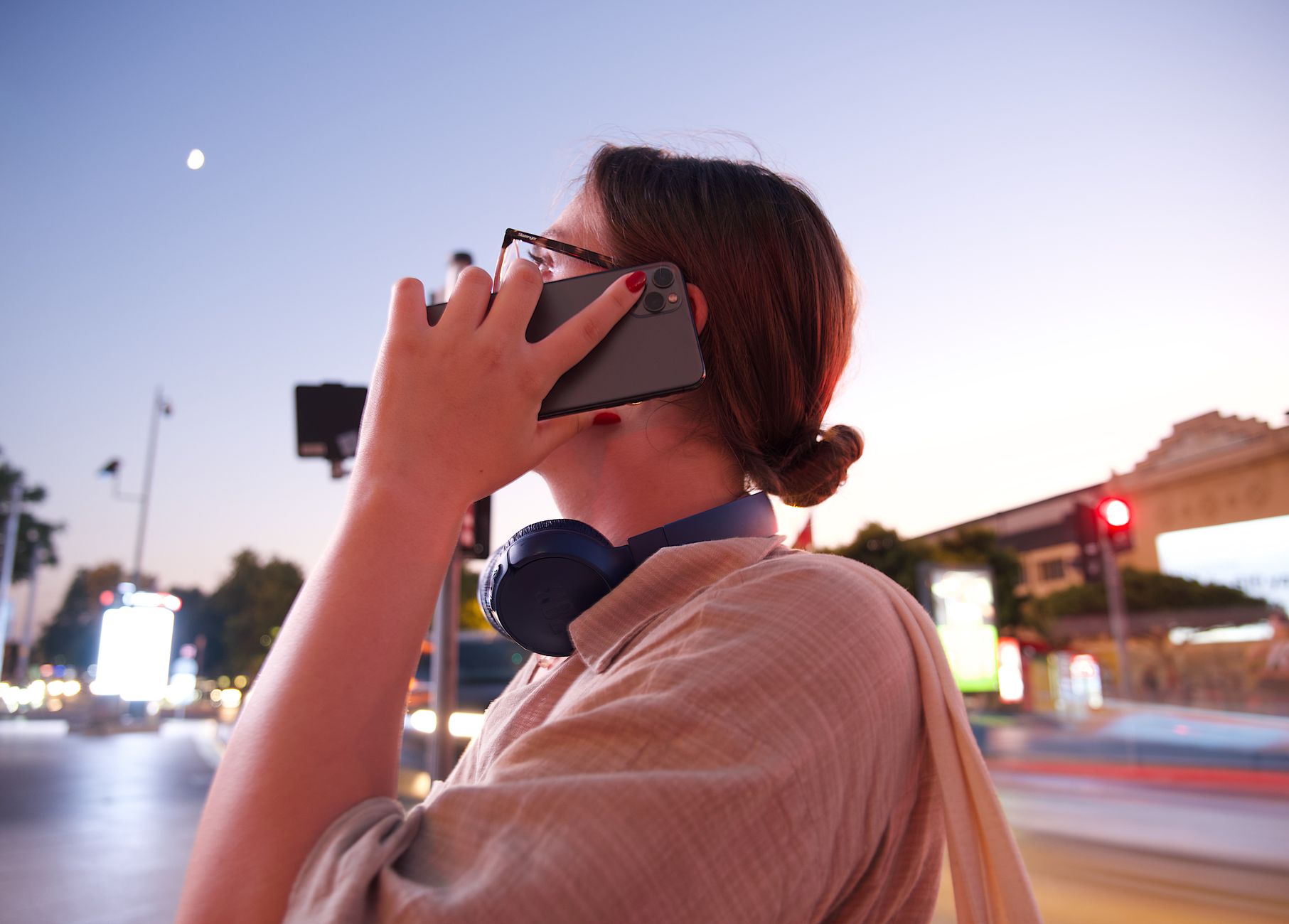 夕暮れの街なかで、スマートフォンを耳に当てて通話している人の後ろ姿