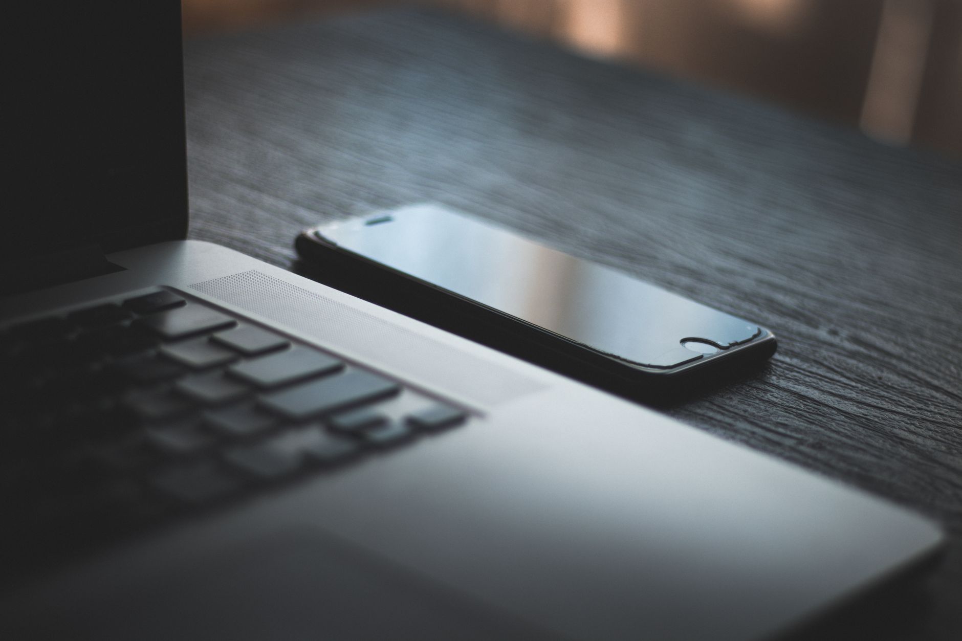 開いたノートパソコンのそばに置かれたスマートフォンのクローズアップ