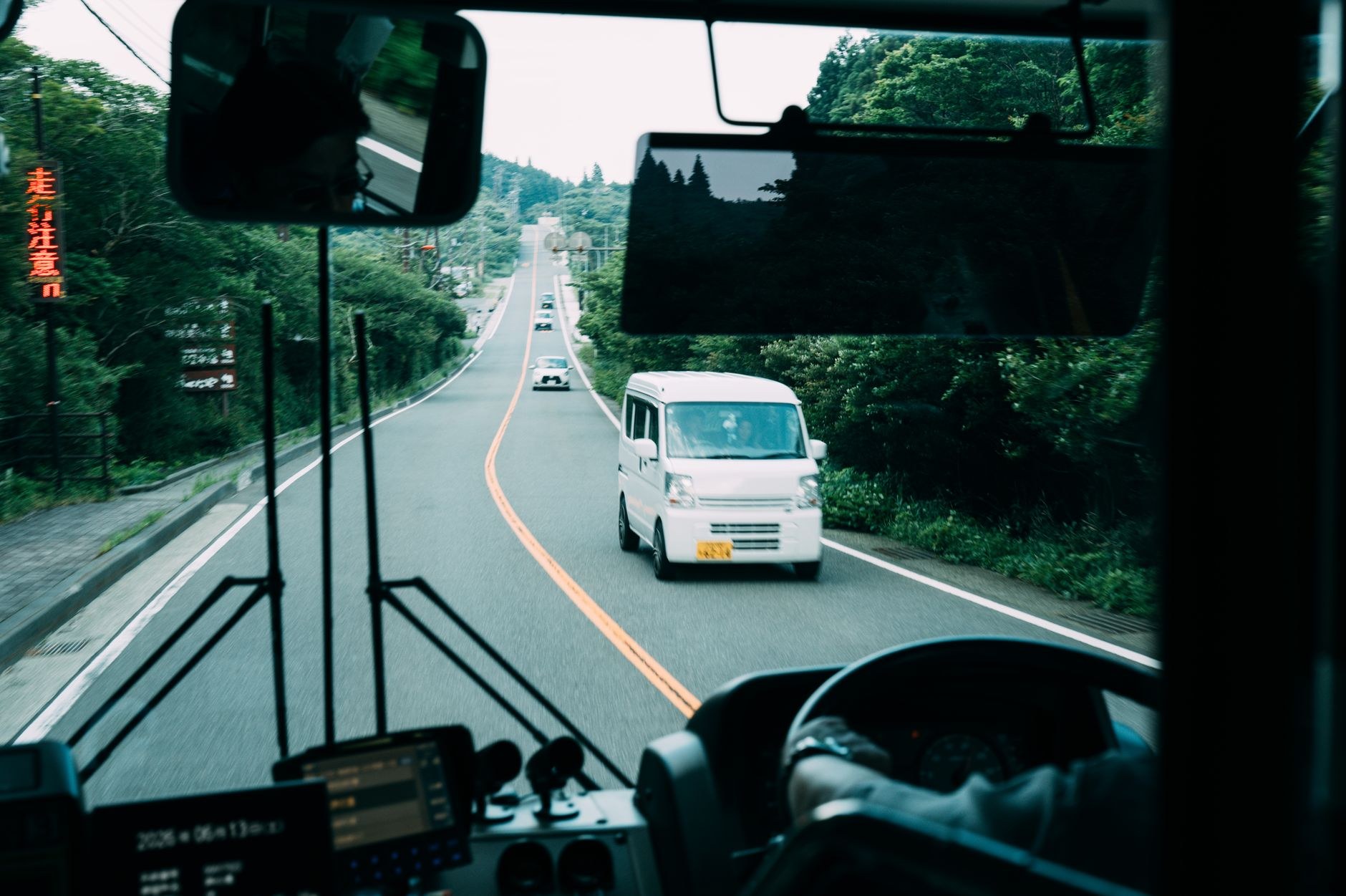 バスの運転席越しに見た日本の一般道。対向車線を軽自動車が走っている（写真はイメージ）