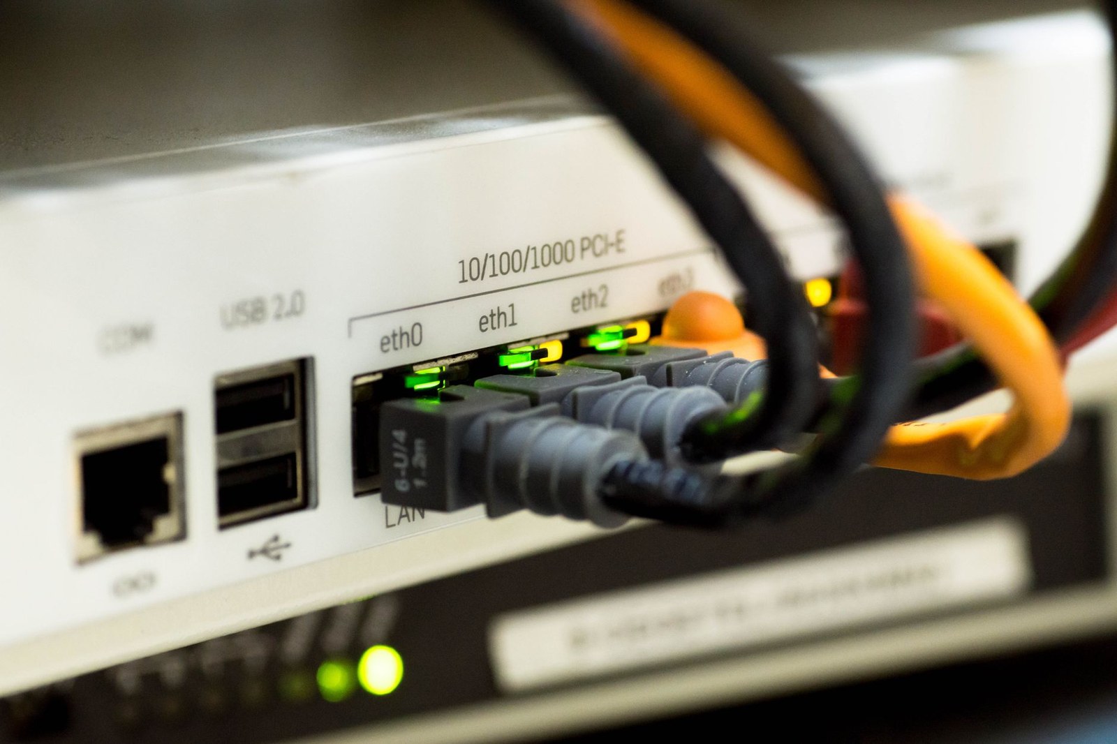 ルーターのLANポートに差し込まれた複数のLANケーブルと、緑色に点灯したリンクランプのクローズアップ