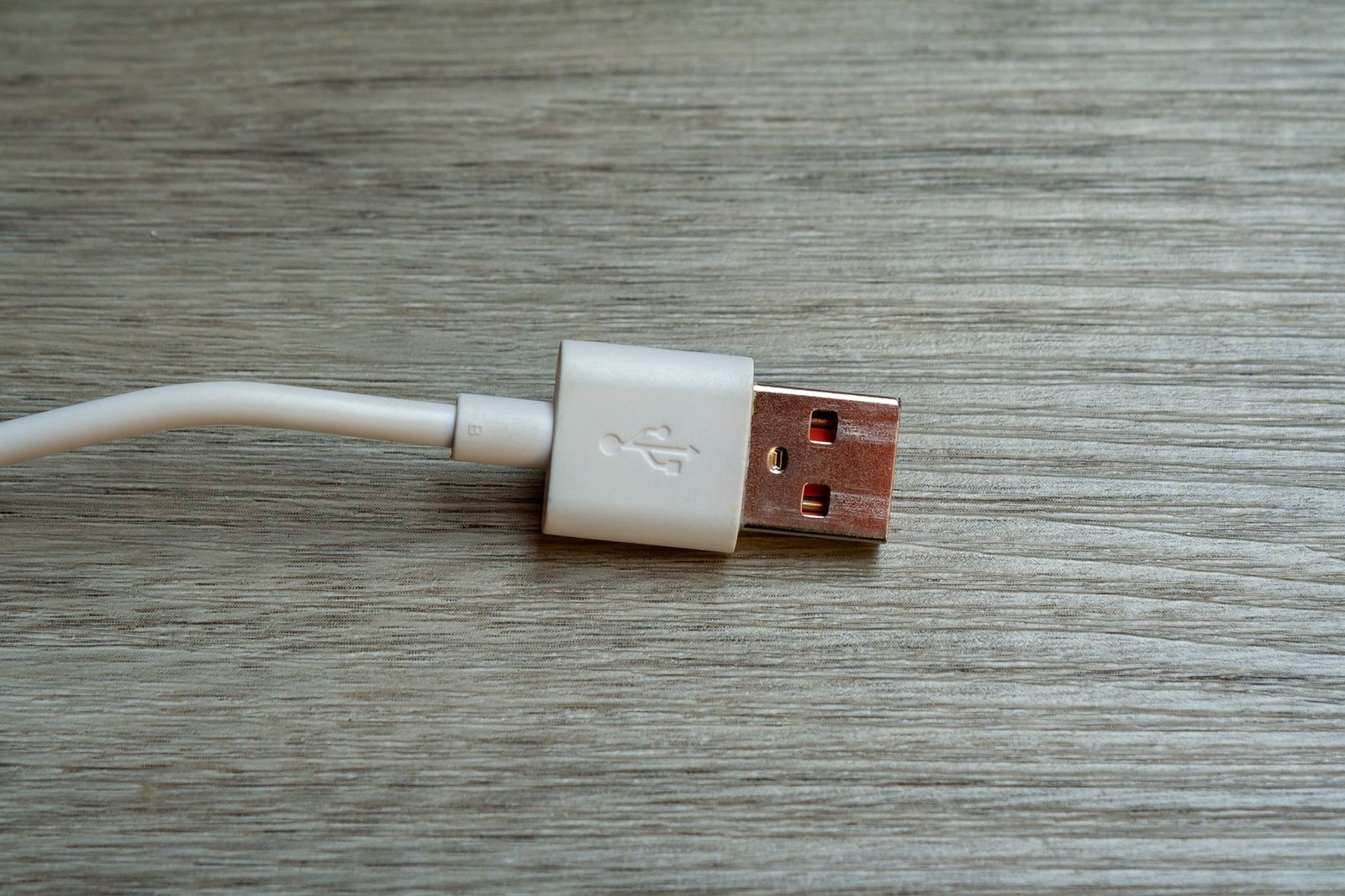 木目のテーブルに置かれた白いUSB Type-Aケーブルのコネクターのクローズアップ
